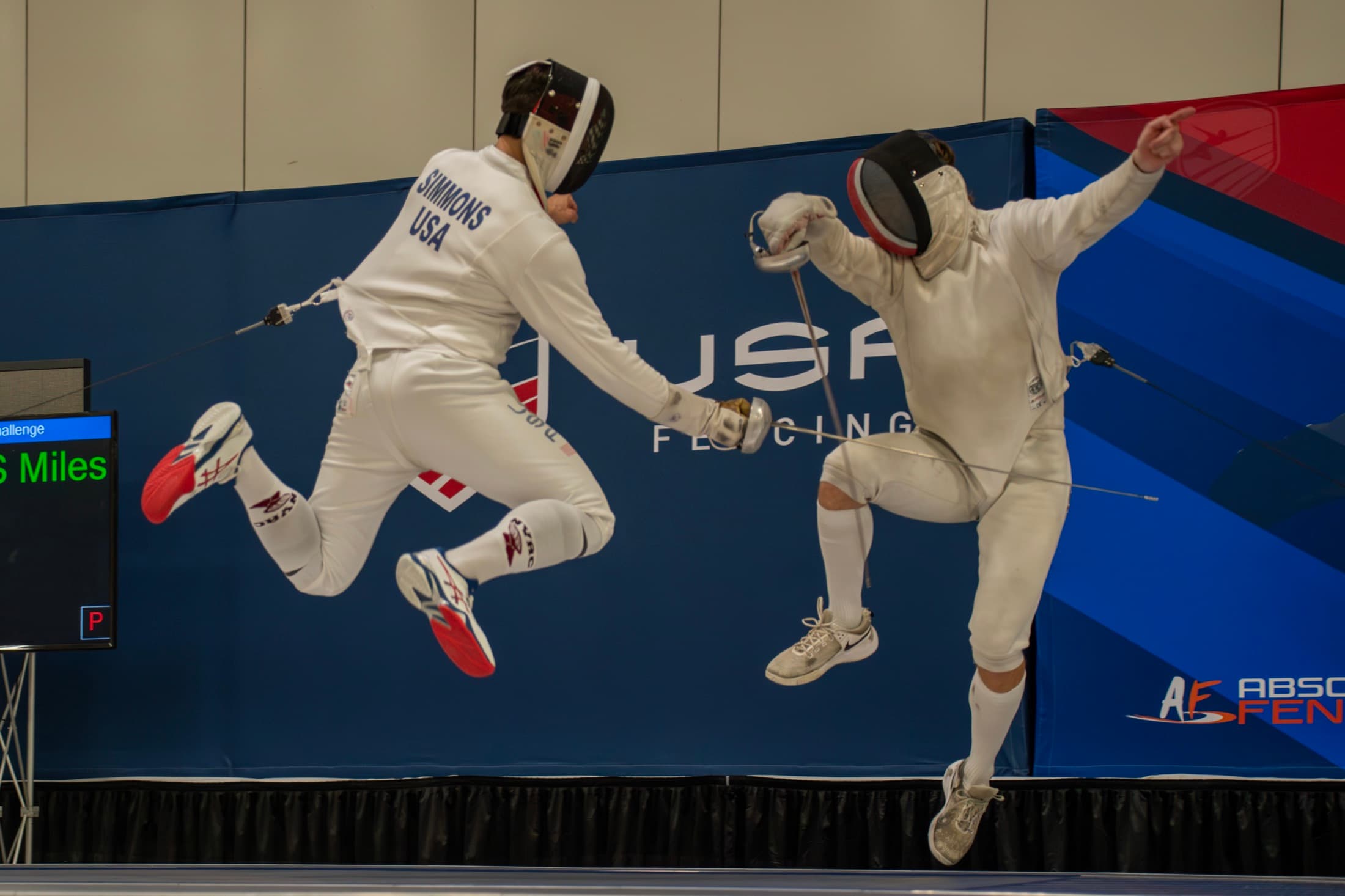 Ari mid-flèche, airborne in a bout at a USA Fencing event